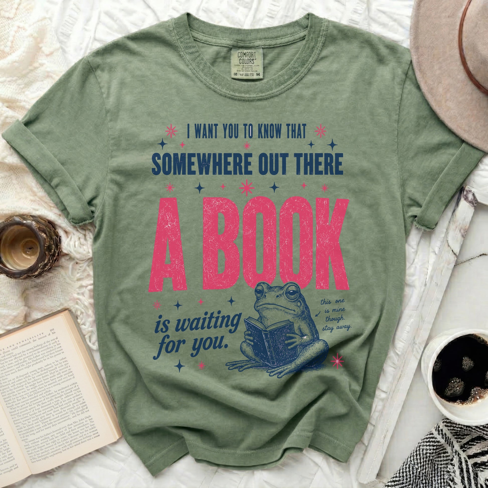 Green t-shirt with a frog reading a book and the text "Somewhere out there a book is waiting for you."
