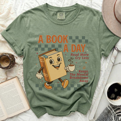 Green t-shirt with "A Book A Day Read More Cry Less Keeps The Mental Breakdown Away" graphic.