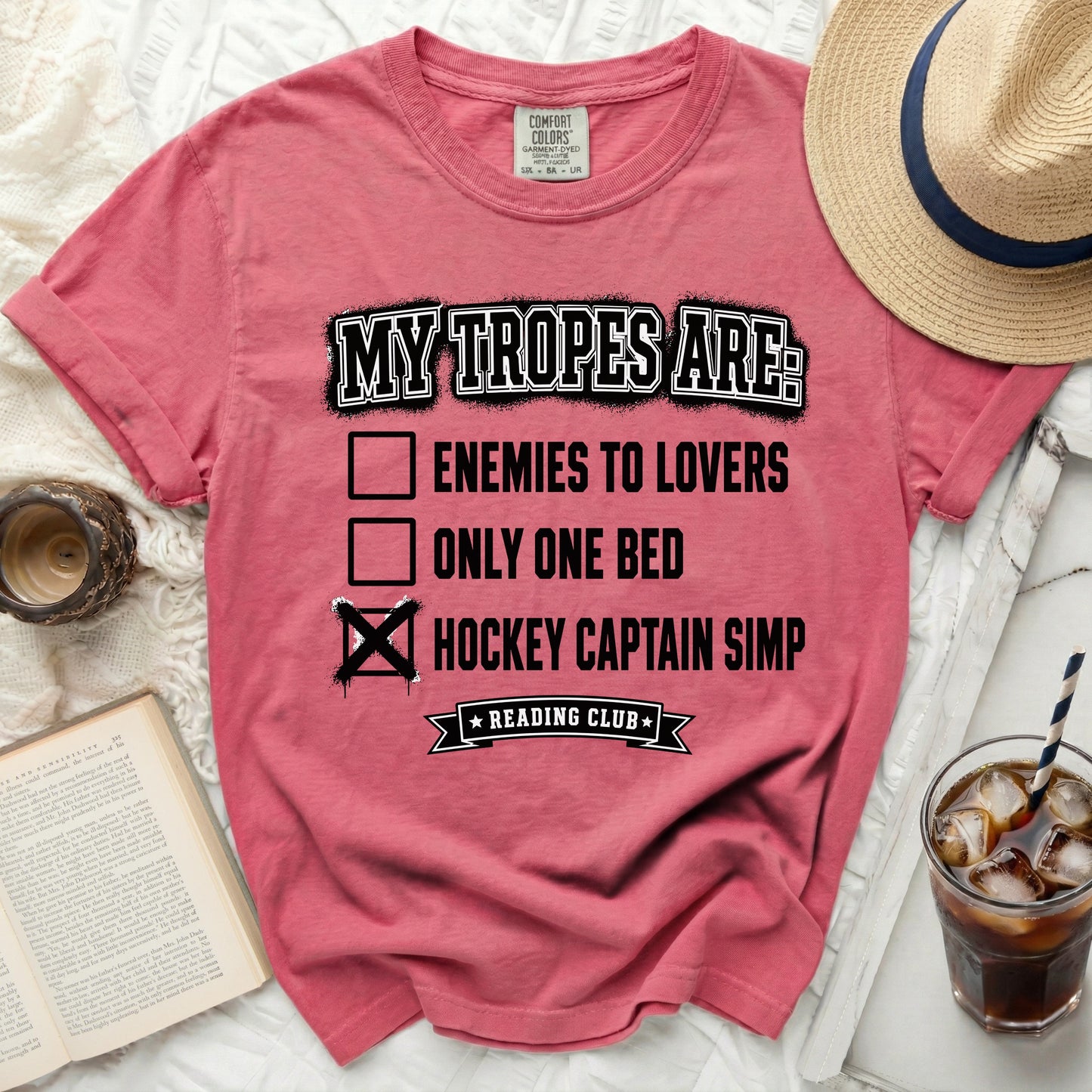 Pink t-shirt with "My Tropes Are: Enemies to Lovers, Only One Bed, Hockey Captain Simp" text.