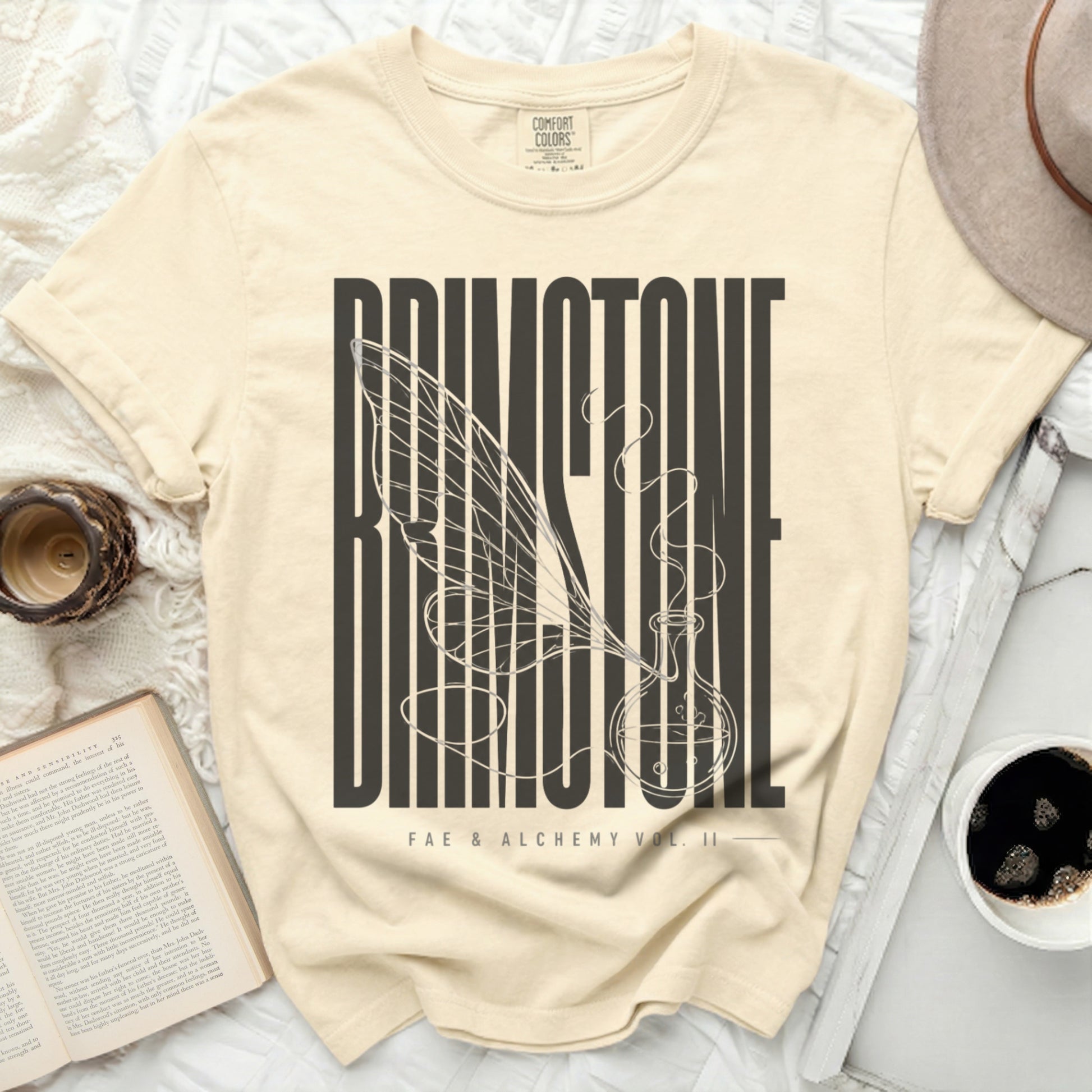 Cream t-shirt with "Brimstone" and a vial with wings graphic.