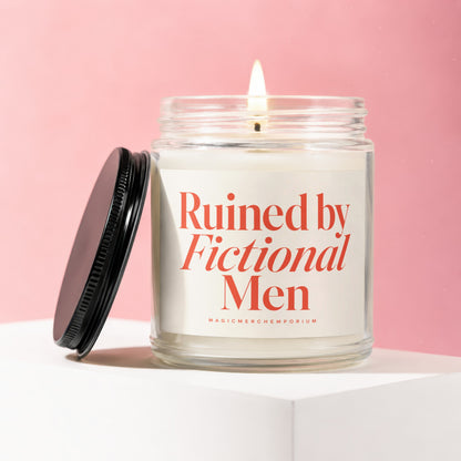 Lit glass candle with red text "Ruined by Fictional Men" on a pink background.