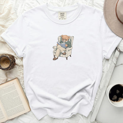 White Comfort Colors t-shirt with illustration of a bear reading in an armchair.