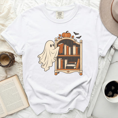White t-shirt with a ghost reaching for a bookshelf and Halloween decorations.