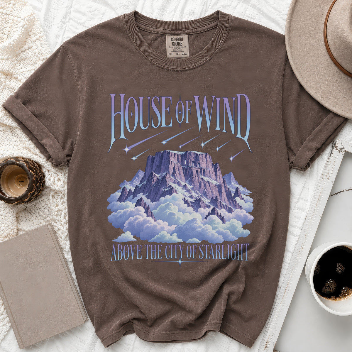 Brown t-shirt with "House of Wind" above a mountain in clouds.
