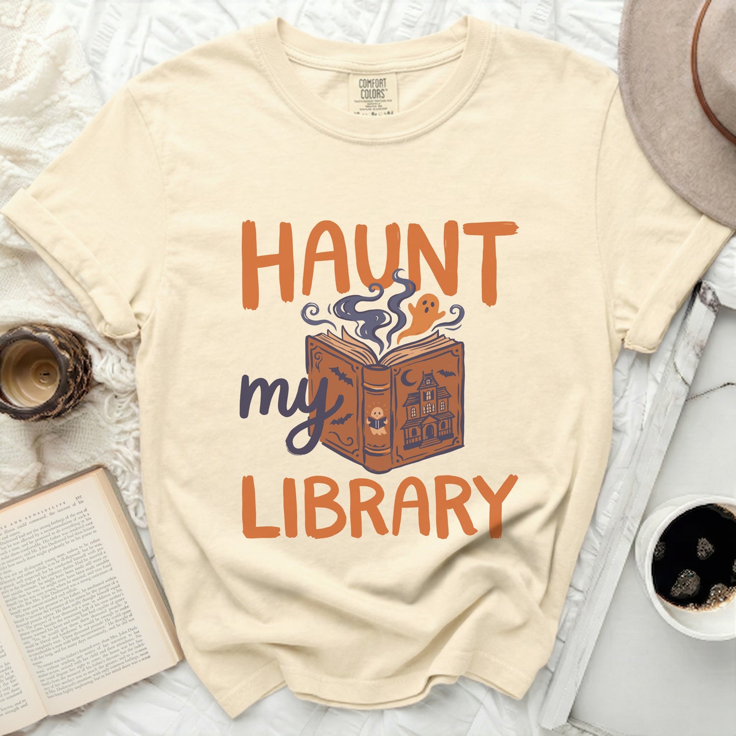 Cream t-shirt with "Haunt my Library" graphic featuring a book and ghost.