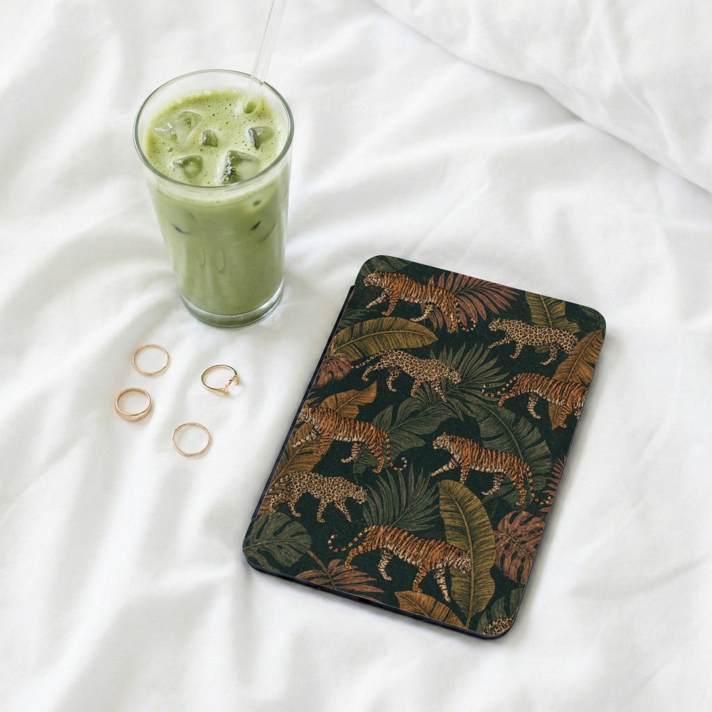 Tablet case with tiger and leopard pattern on dark green background, next to a green drink.