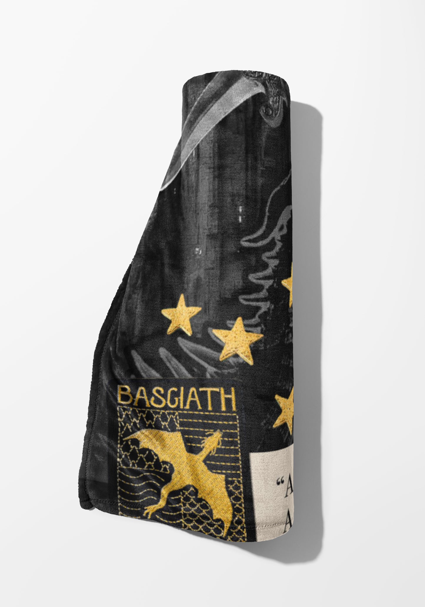Rolled black blanket with gold stars, dragon, and "BASGIATH" text.