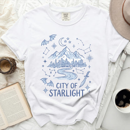 White t-shirt with blue graphic of a city, mountains, stars, and text "City of Starlight".