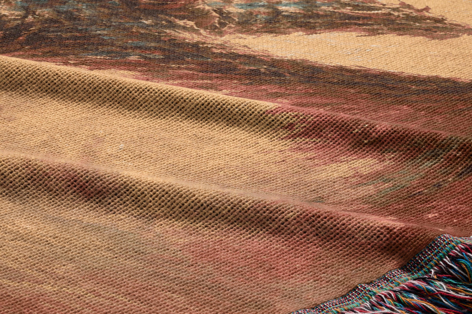 a close-up view of a textured fabric, possibly a blanket or rug, with a colorful abstract pattern. The fabric appears to be made of wool or a similar material, and the pattern consists of various shades of brown, red, and beige. The fabric has a slightly wrinkled texture, giving it a cozy and comfortable appearance.