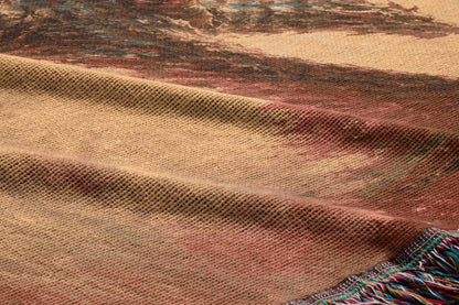 a close-up view of a textured fabric, possibly a blanket or rug, with a colorful abstract pattern. The fabric appears to be made of wool or a similar material, and the pattern consists of various shades of brown, red, and beige. The fabric has a slightly wrinkled texture, giving it a cozy and comfortable appearance.