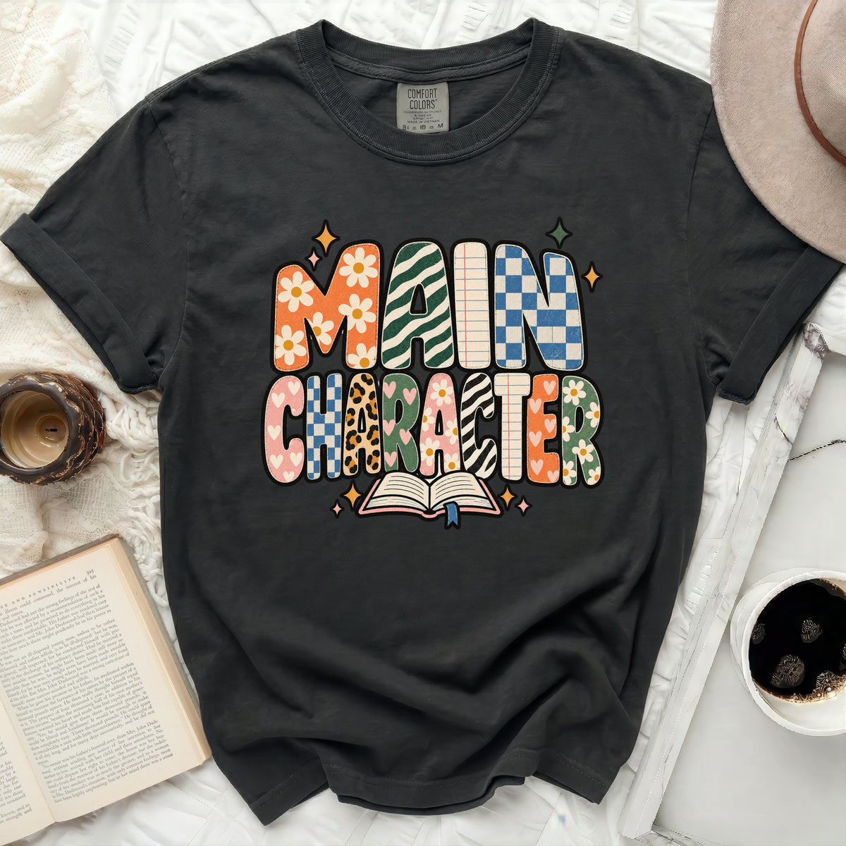 Dark gray t-shirt with colorful "Main Character" text and open book graphic.