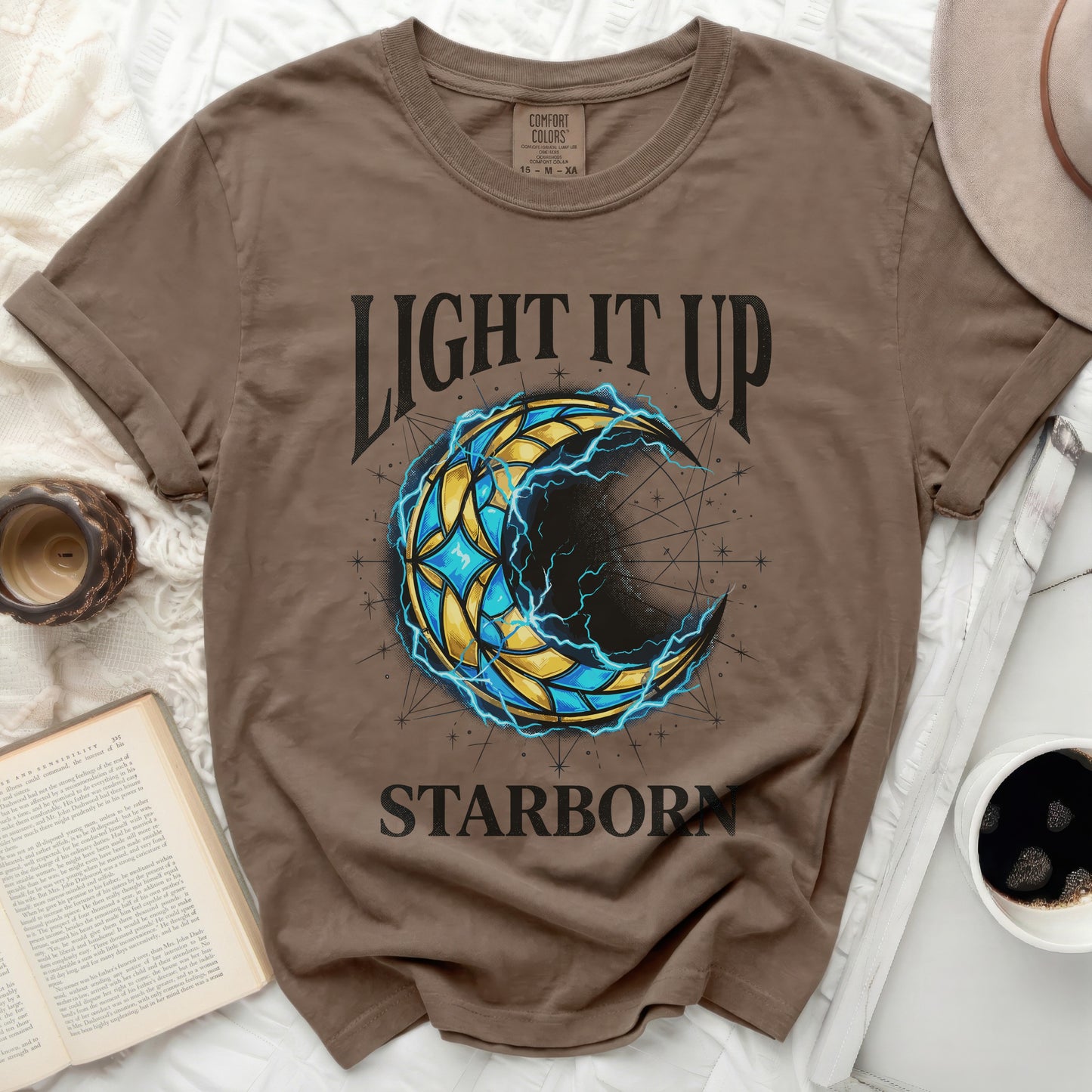 Brown t-shirt with "LIGHT IT UP STARBORN" and celestial crescent moon design.
