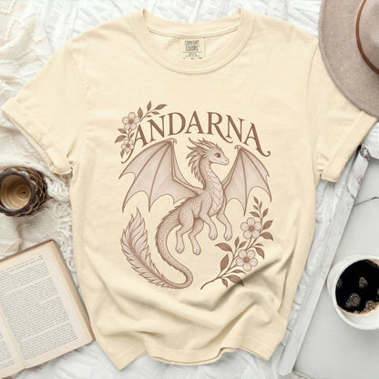 Beige t-shirt featuring a brown vintage-style drawing of a winged dragon, flowers, and the word ANDARNA.