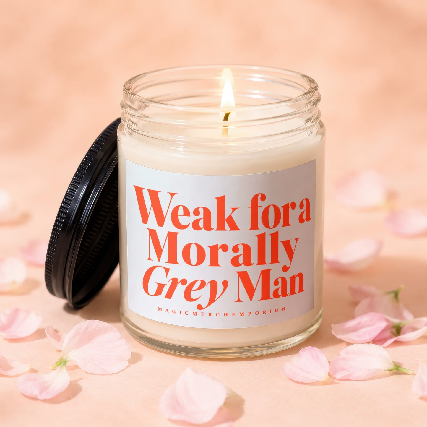 Candle with lid off and lit flame, reads "Weak for Morally Grey Man"