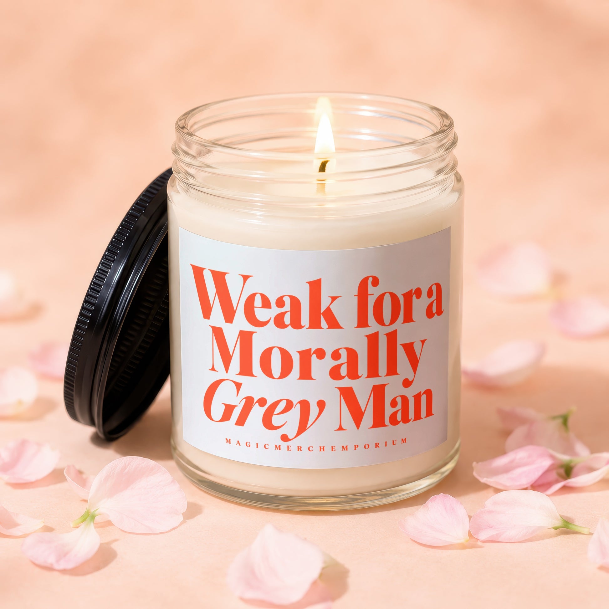 Candle with lid off and lit flame, reads "Weak for Morally Grey Man"