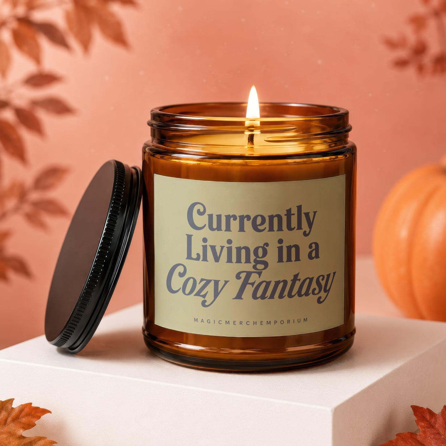 Amber glass candle with lit wick and label that reads "Currently Living in a Cozy Fantasy".