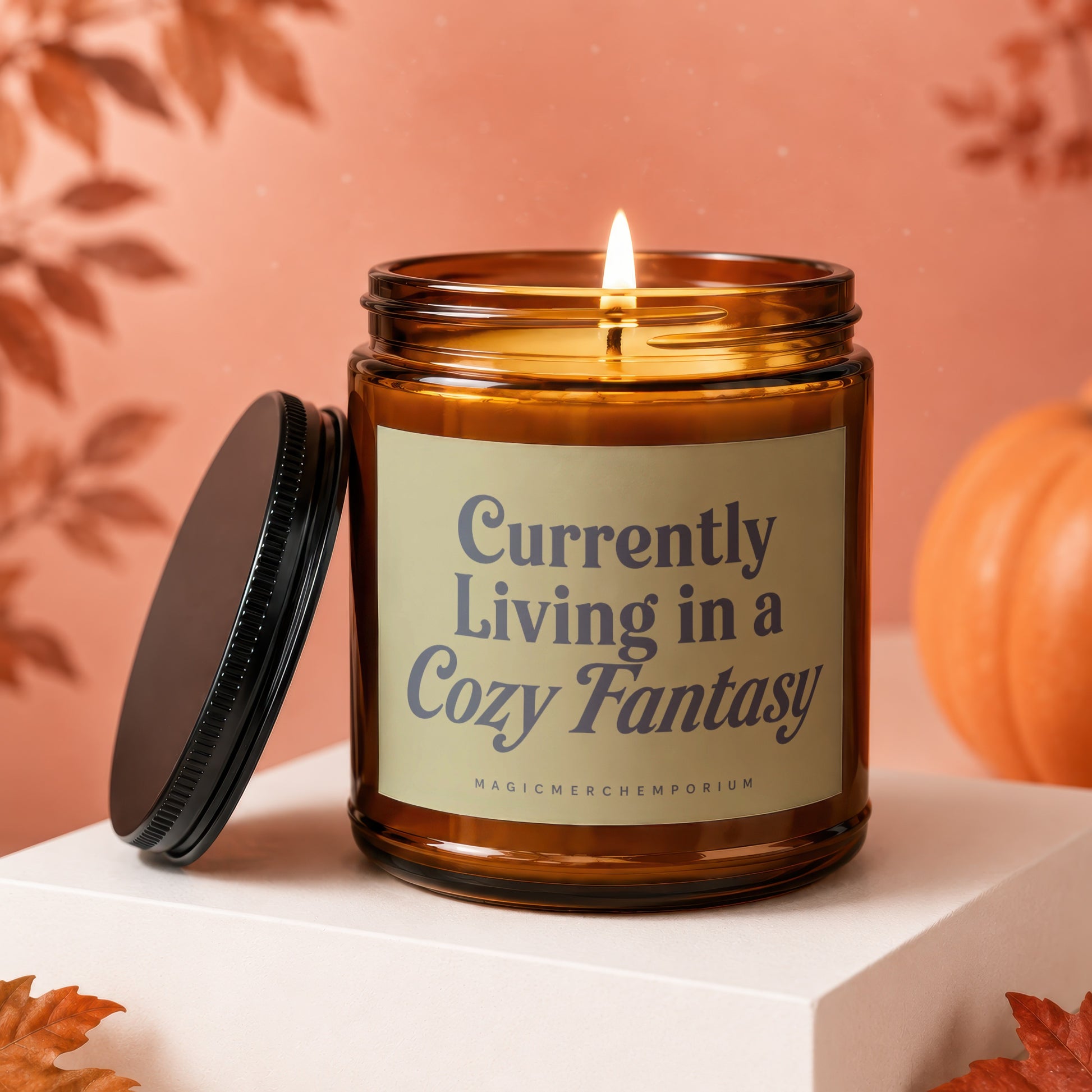 Amber glass candle with lit wick and label that reads "Currently Living in a Cozy Fantasy".