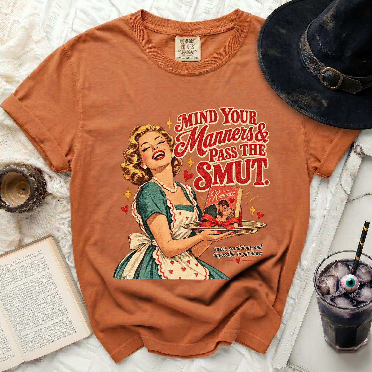 Orange t-shirt with graphic of a laughing woman holding a romance novel.