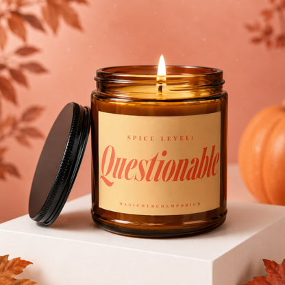 Amber candle with "Spice Level: Questionable" label on display pedestal near a pumpkin.