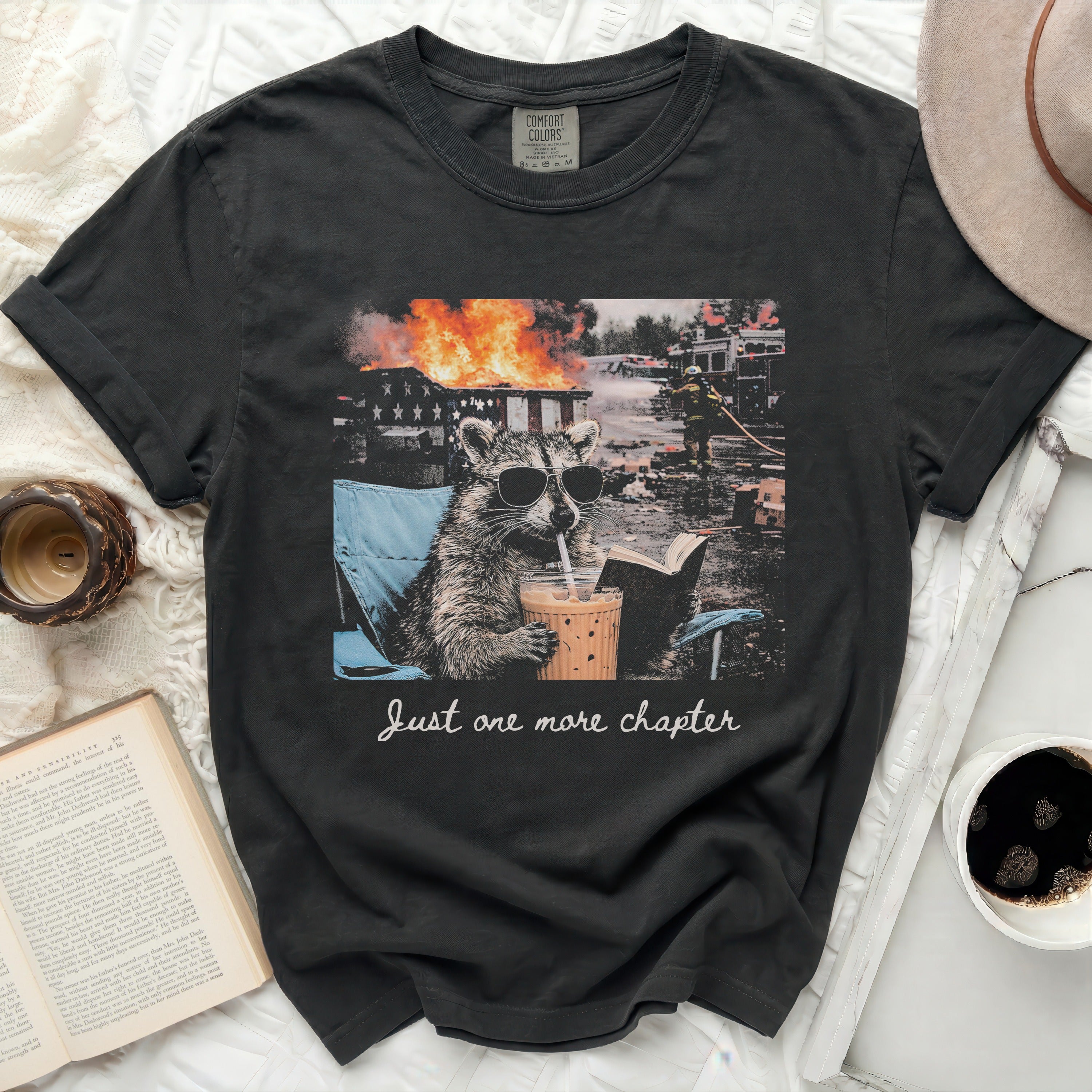 T-shirt with raccoon in a chair, coffee, and fire, reads 