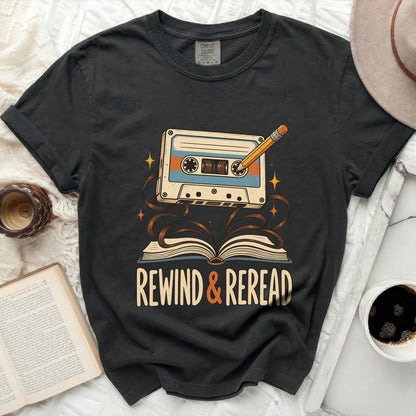 Graphic t-shirt with a cassette tape, pencil, open book, and text "Rewind & Reread".