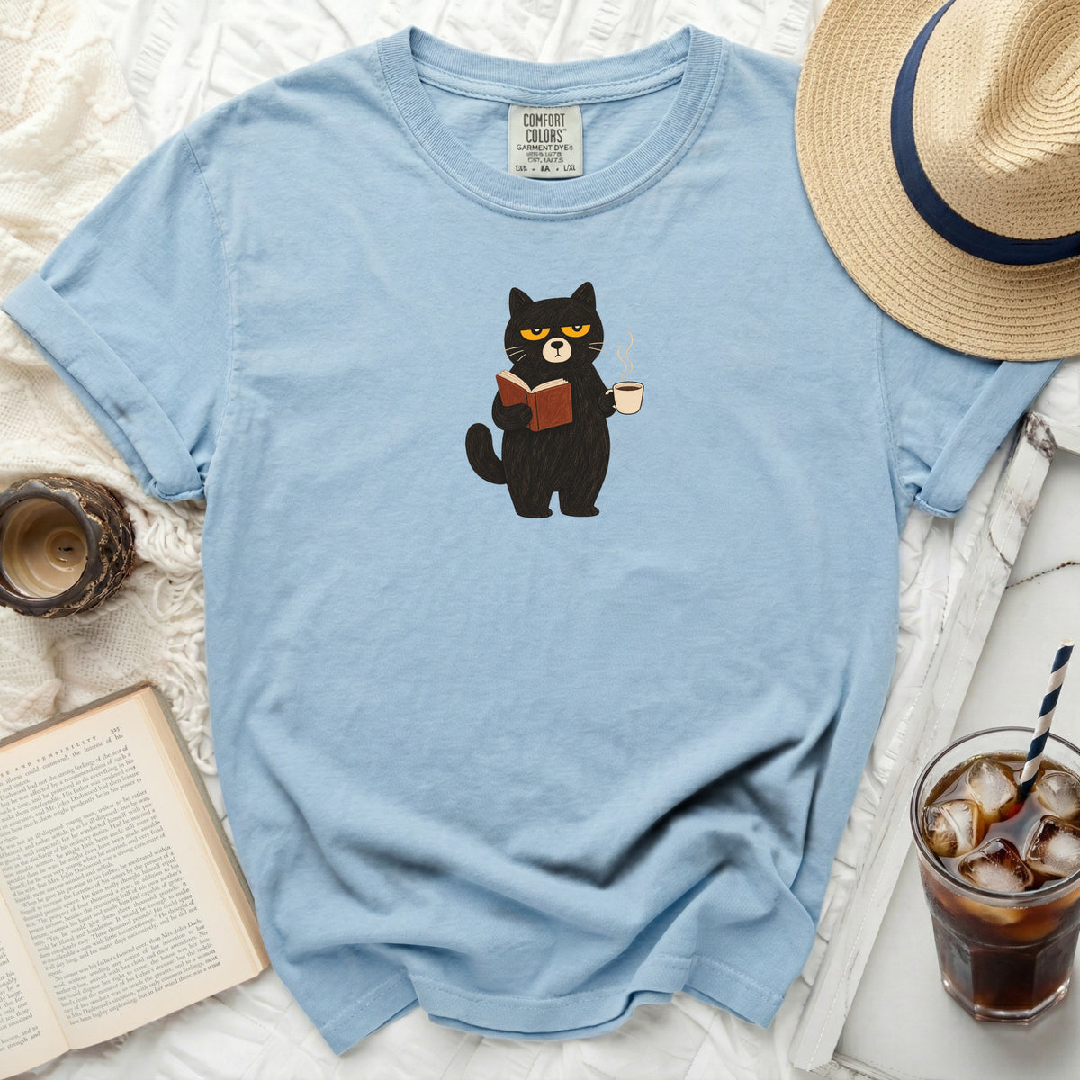 Light blue t-shirt with a grumpy black cat reading and holding coffee.