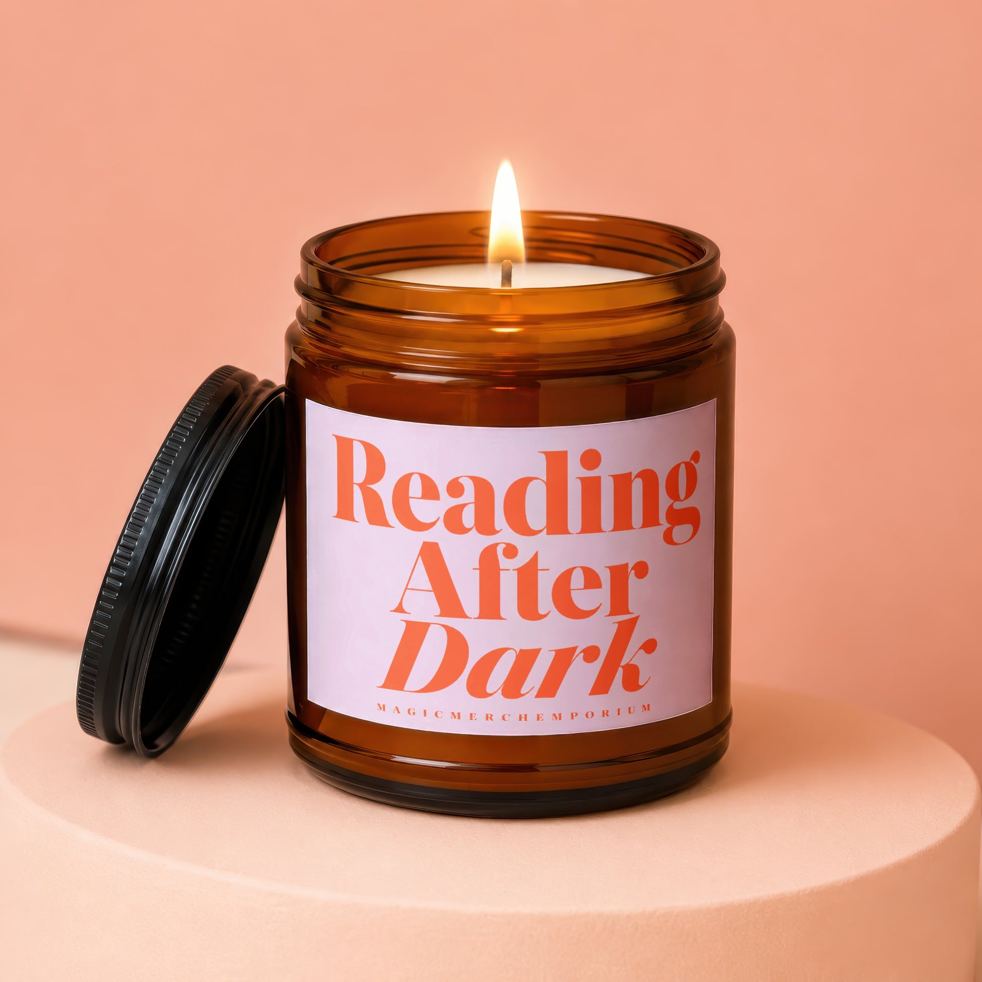 Lit amber jar candle with black lid, reading "Reading After Dark".