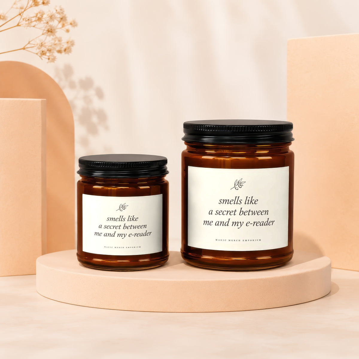 Two amber glass candles with black lids, each labeled "smells like a secret between me and my e-reader".