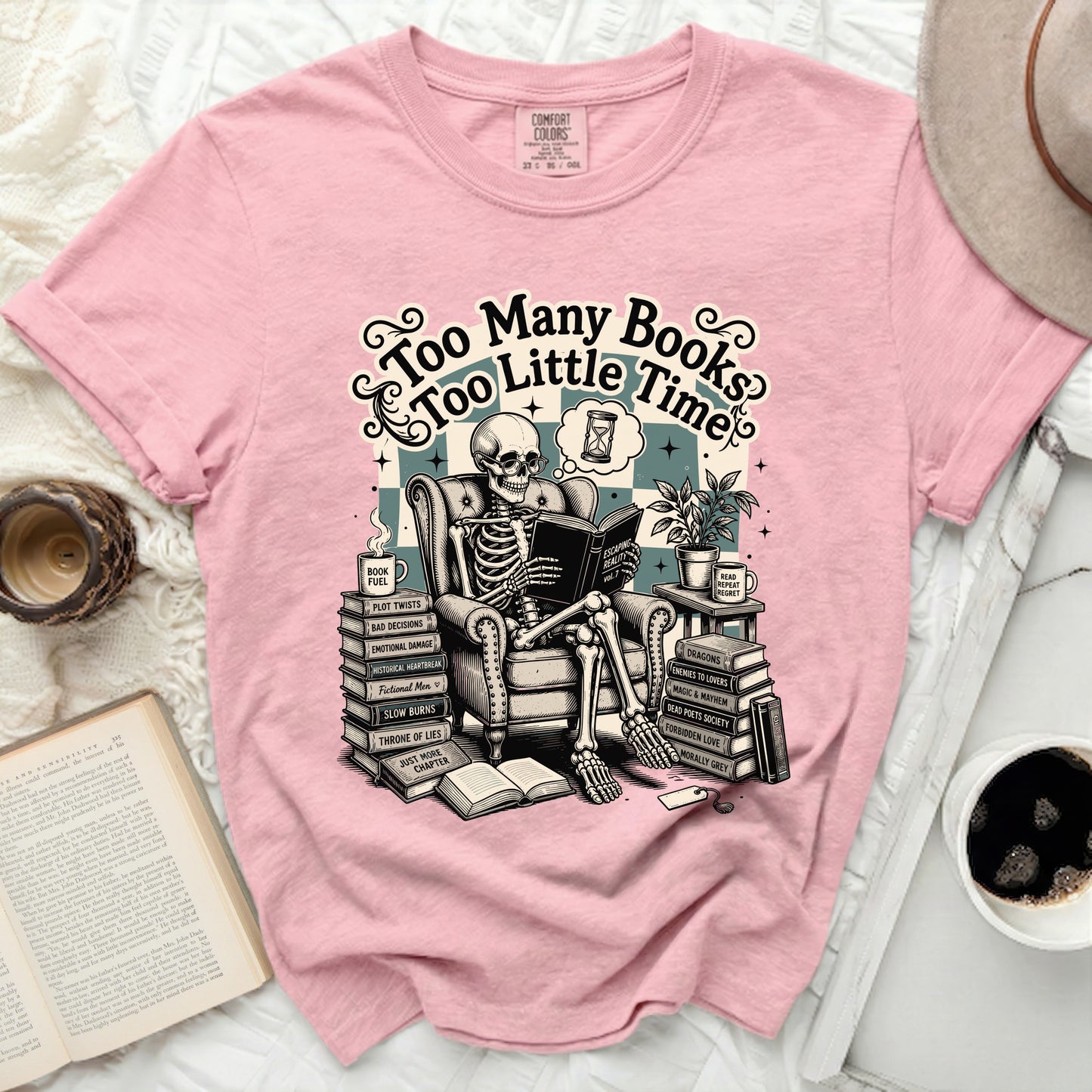 Pink t-shirt with skeleton reading "Too Many Books Too Little Time" graphic.