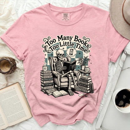 Pink t-shirt with skeleton reading "Too Many Books Too Little Time" graphic.