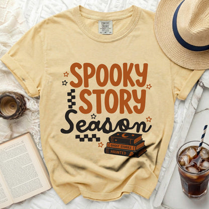 Yellow t-shirt with "Spooky Story Season" graphic and stack of books.