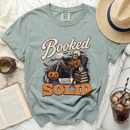 Skeleton reading a book with text "Booked" and "Currently Avoiding People Solid".