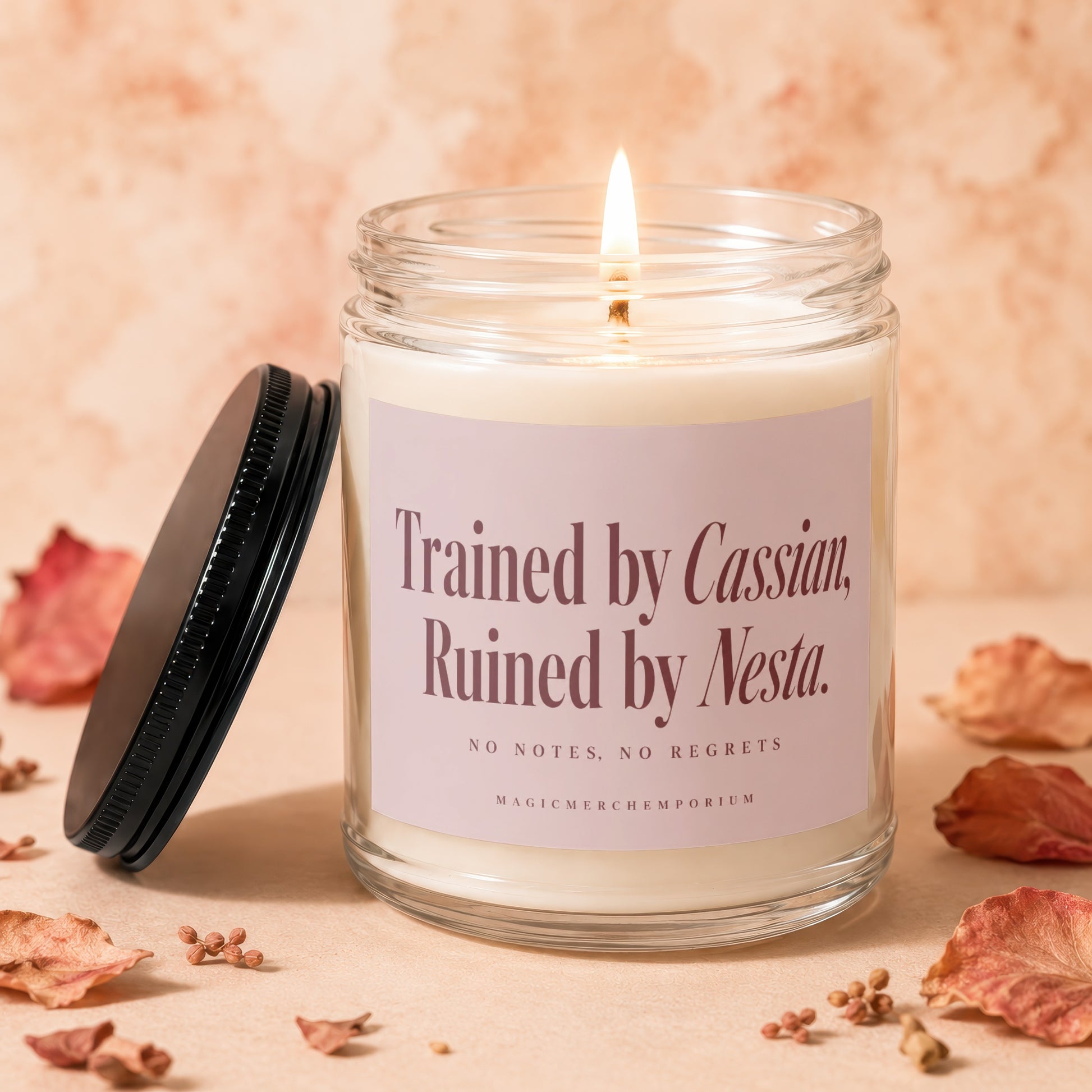 A lit soy wax candle in a clear glass jar with a black lid, surrounded by dried rose petals.