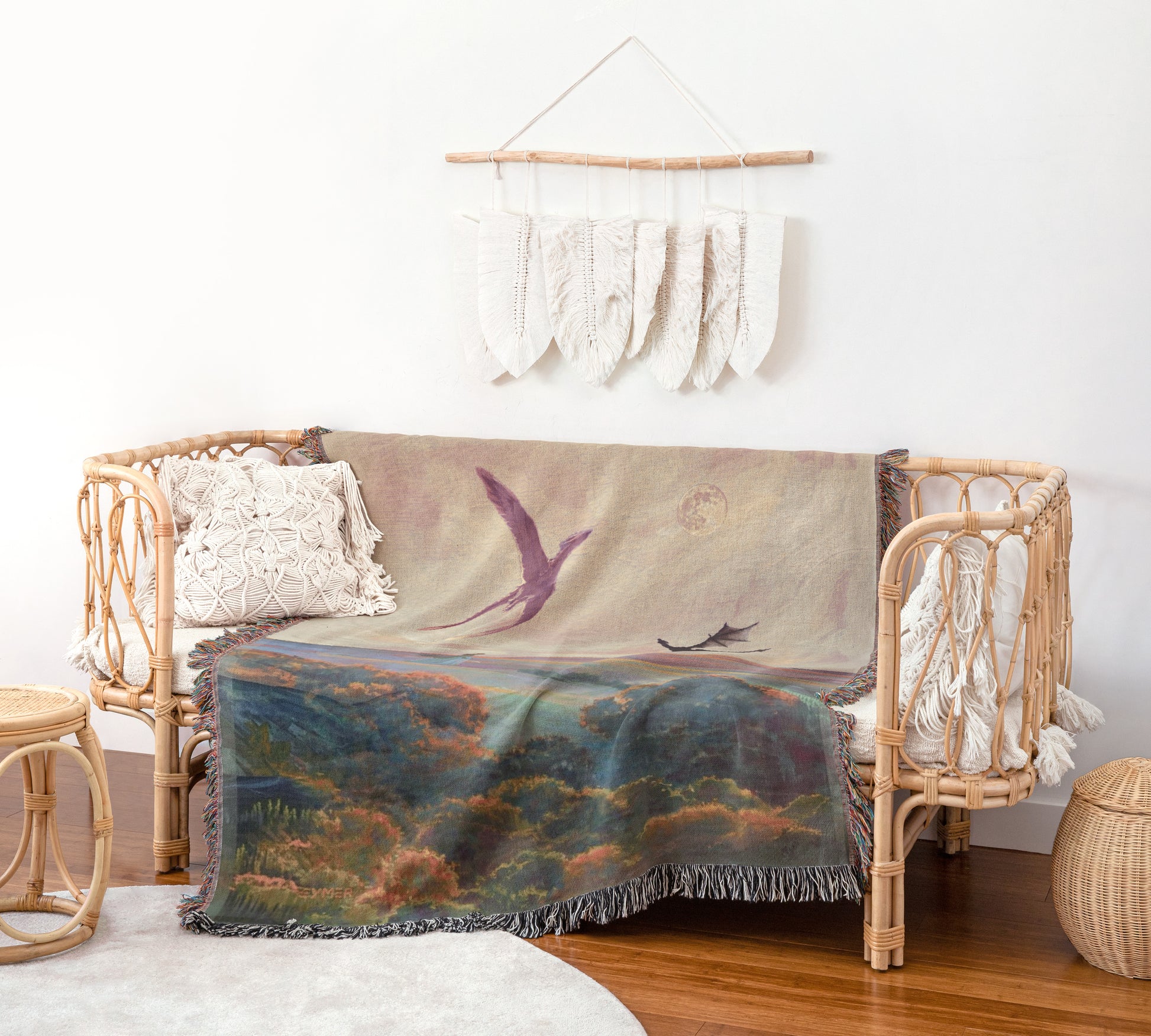 a cozy living room with a wicker sofa adorned with a colorful throw blanket and a white wall hanging with white feathers.