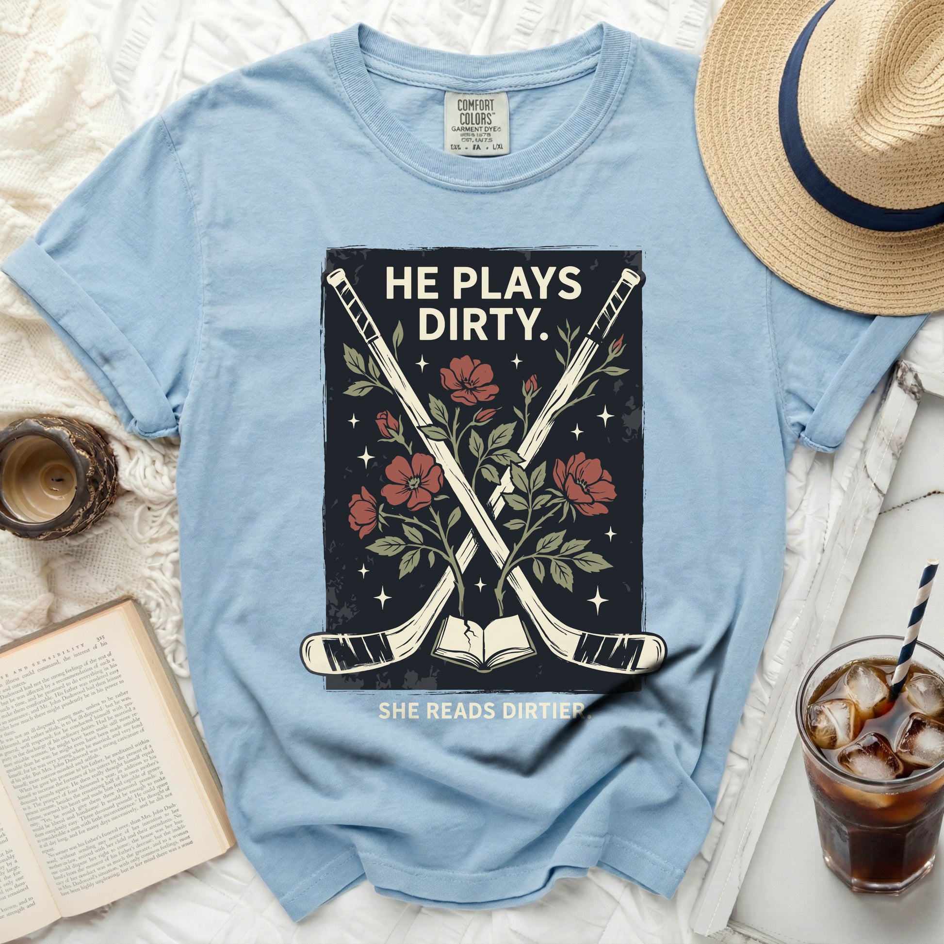 Blue t-shirt with hockey sticks, flowers, and text "HE PLAYS DIRTY. SHE READS DIRTIER."