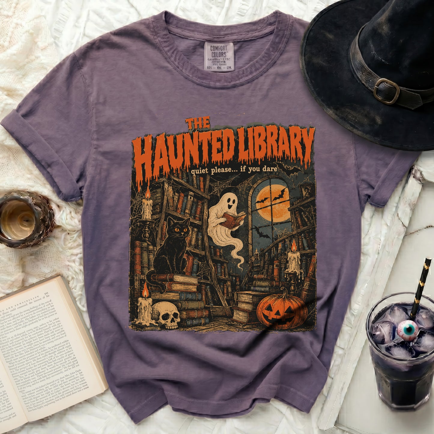 The Haunted Library t-shirt with ghost, cat, pumpkin, and skull graphic.