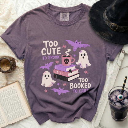 Purple t-shirt with "Too cute to spook, too booked to care" Halloween graphic.