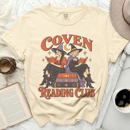Cream t-shirt with graphic of two witches reading, text says "Coven Reading Club".