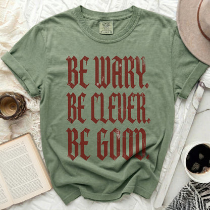 Green t-shirt with "BE WARY. BE CLEVER. BE GOOD." in distressed red gothic font.