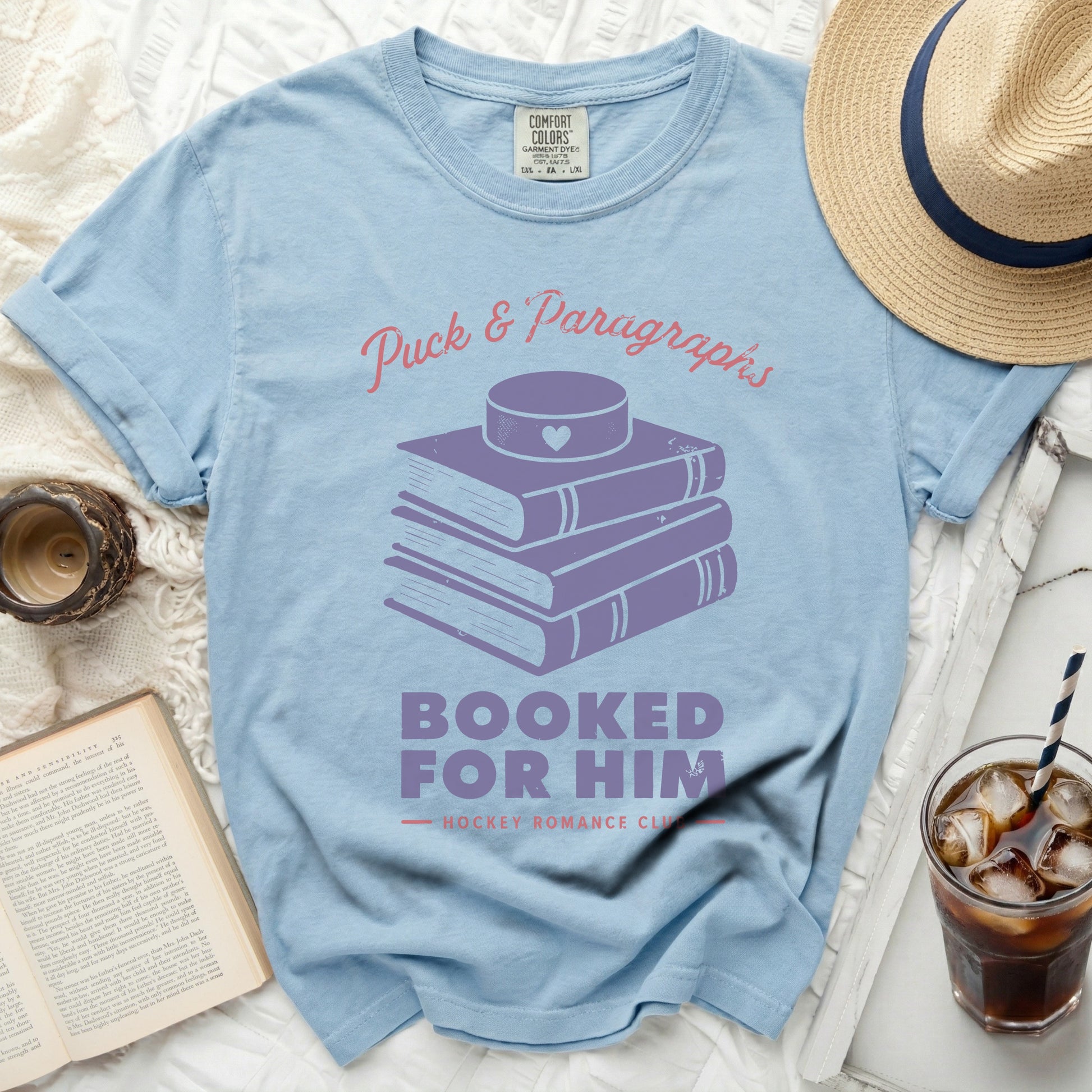 Light blue t-shirt with stacked books and text "Puck & Paragraphs Booked for Him".