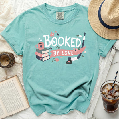 Teal t-shirt with "Booked by Love" text, books, and hockey stick graphic.