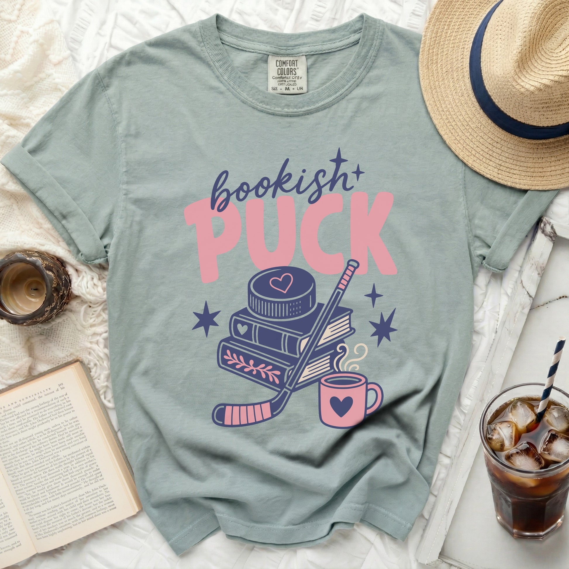 T-shirt with "bookish+ PUCK" text, hockey stick, books, and heart mug.