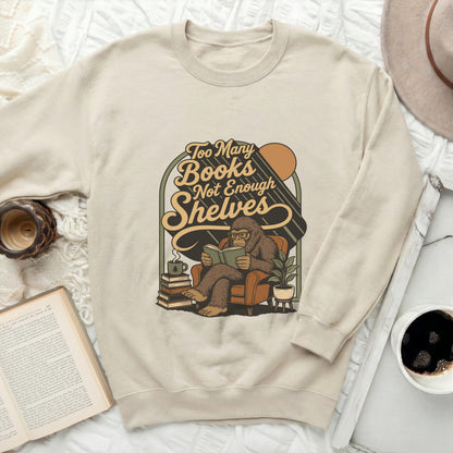 Beige sweatshirt with "Too Many Books Not Enough Shelves" graphic featuring Bigfoot.