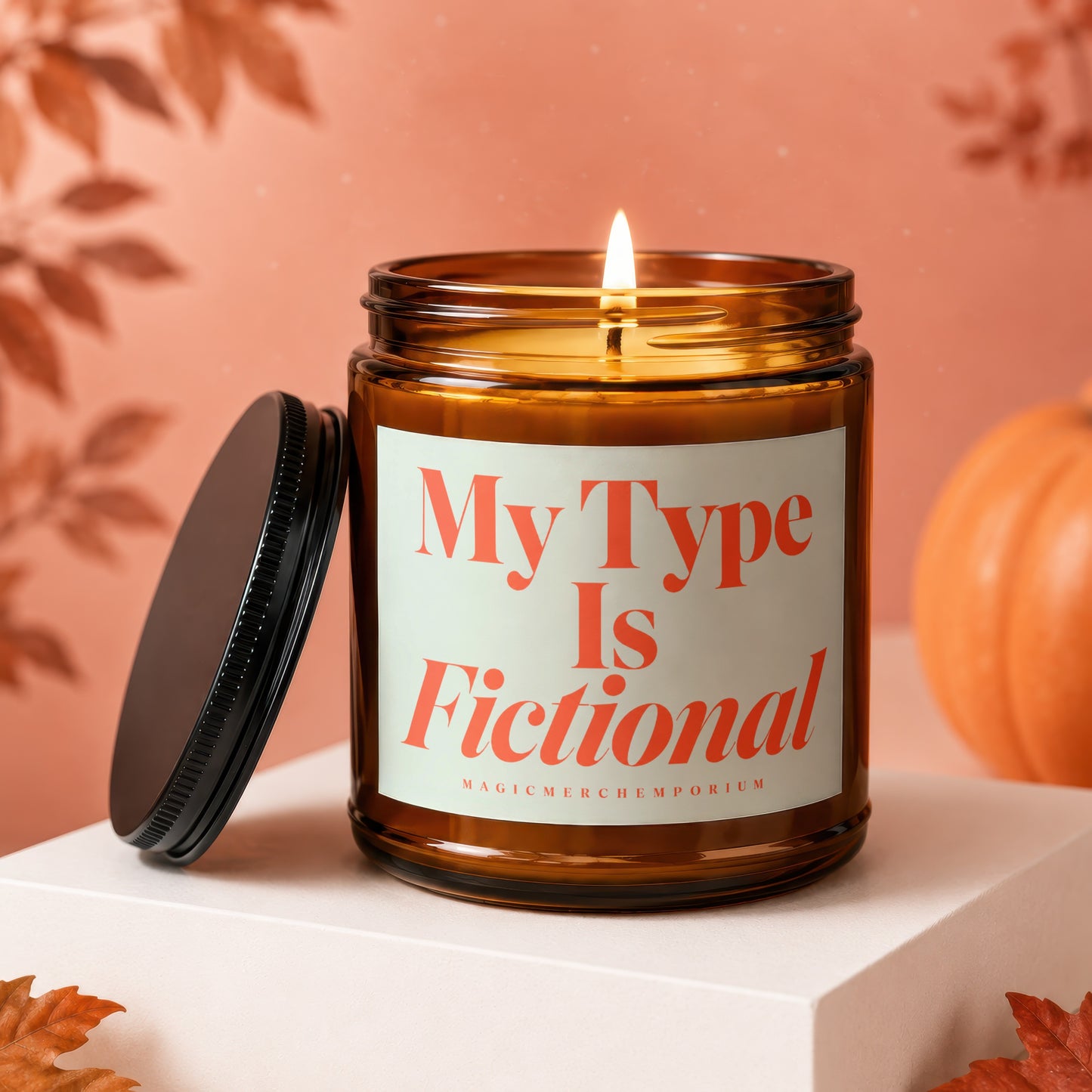 Candle with lid off, "My Type Is Fictional" text, pumpkin, and autumn leaves.