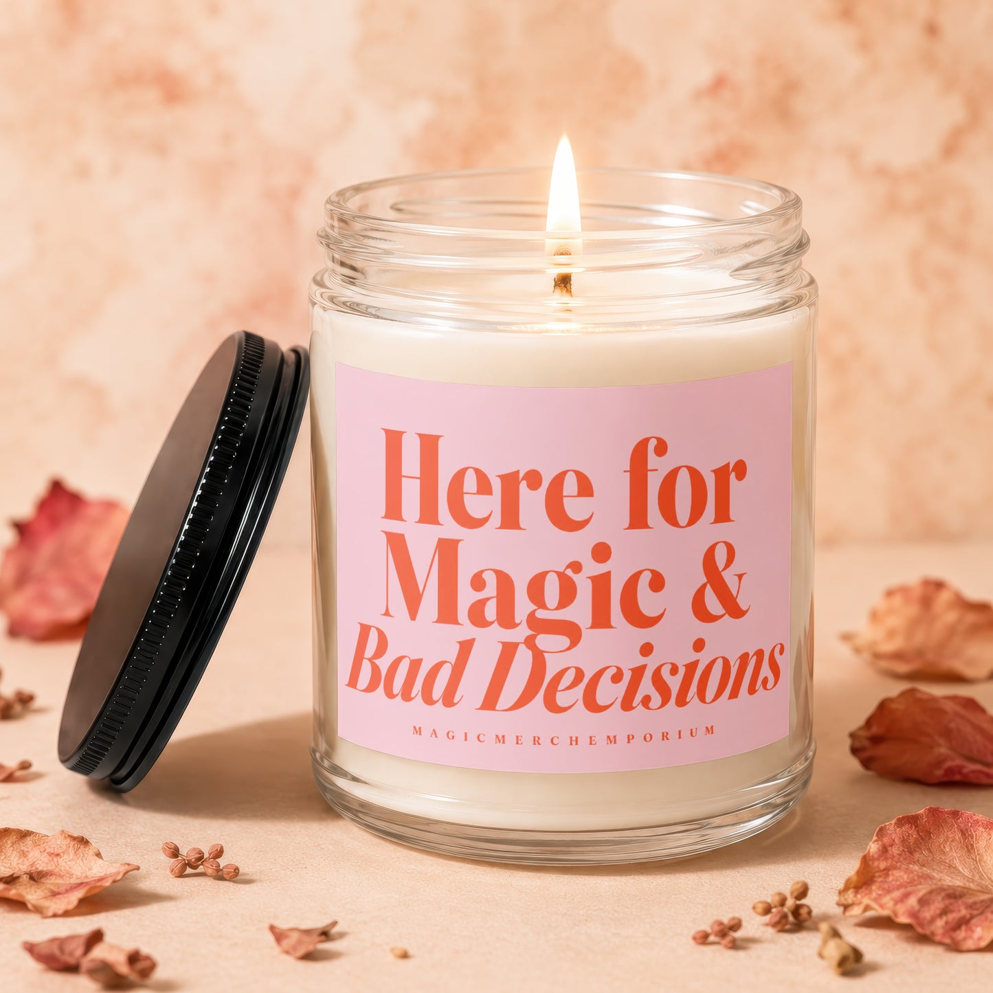 Glass candle with pink label reading "Here for Magic & Bad Decisions".