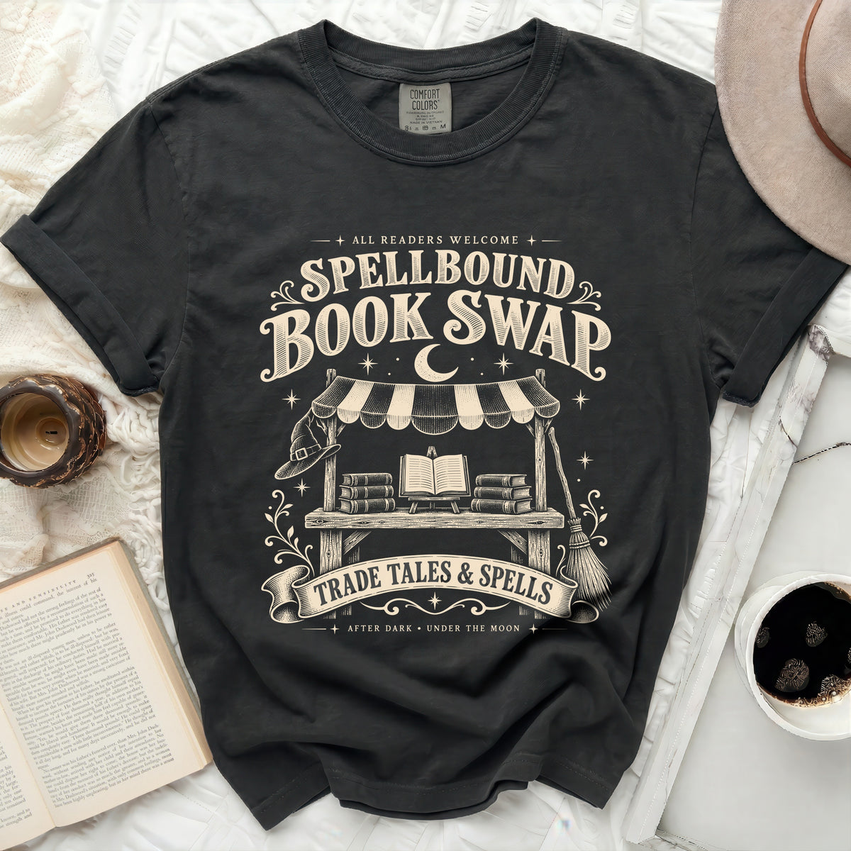 Black t-shirt with "Spellbound Book Swap" and "Trade Tales & Spells" graphics.