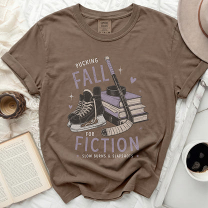 Brown t-shirt with "Pucking Fall Fiction" text, hockey skates, stick, and books.