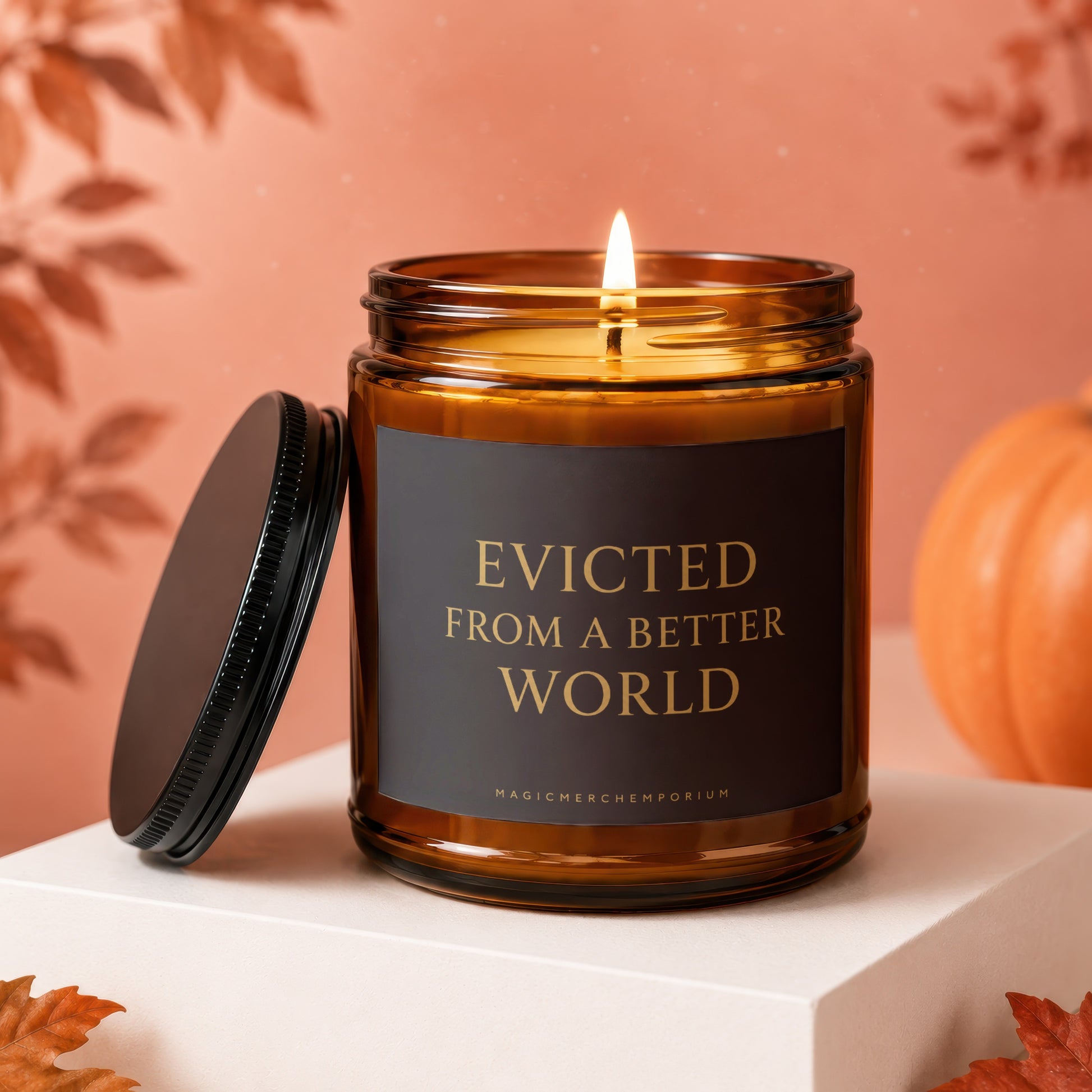 Amber jar candle with lit wick and text "EVICTED FROM A BETTER WORLD".