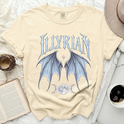 Cream t-shirt with blue "ILLYRIAN" text, dragon wings, and moons.