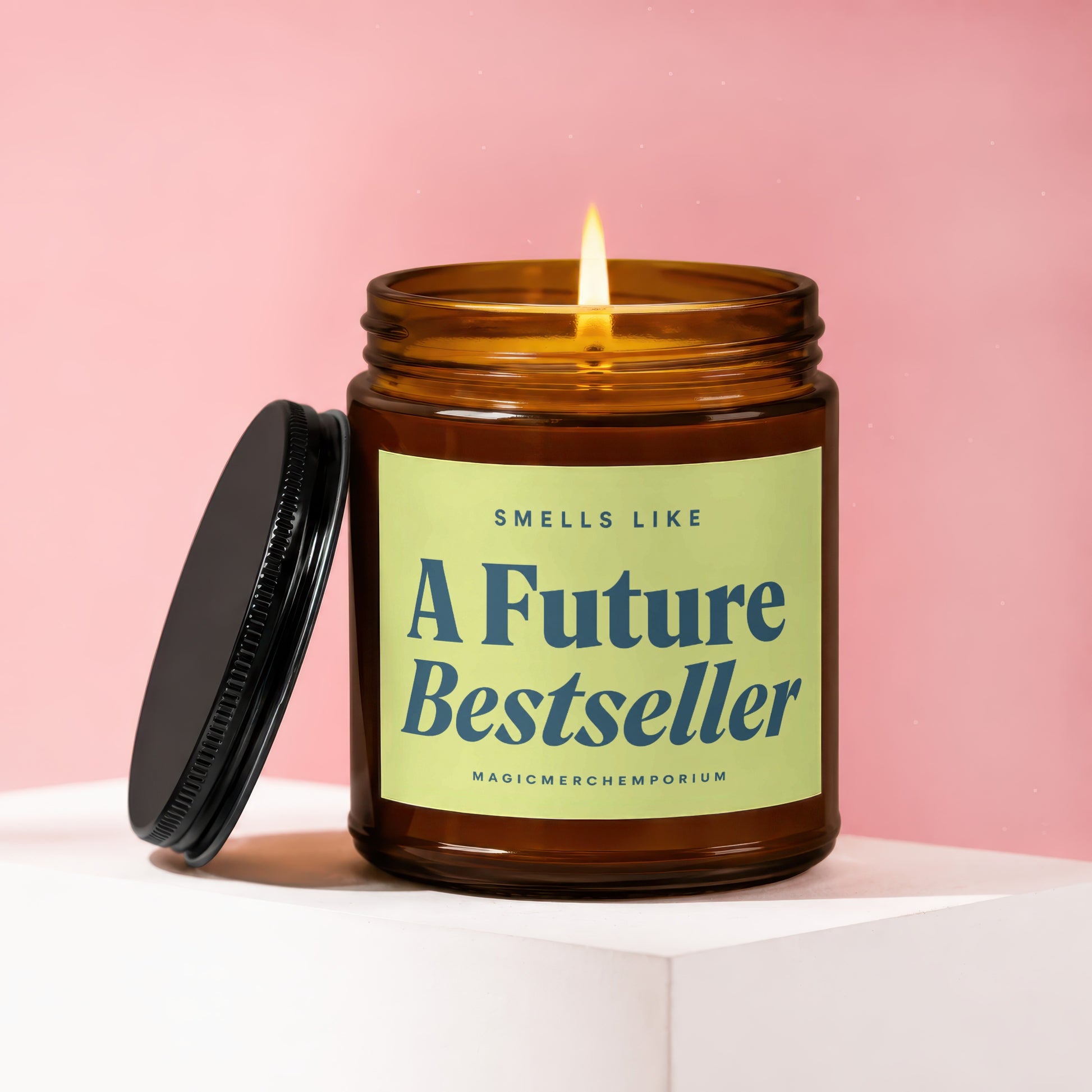 Amber candle with lit wick, label reads "A Future Bestseller" and "MAGICMERCHEPORIUM".